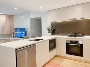 A modern kitchen with built-in appliances, a dishwasher, and a flat-screen TV.