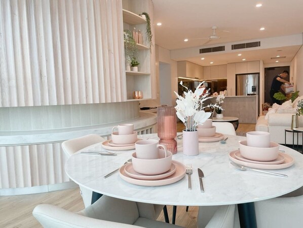 A modern dining area with a round table set for four, featuring pink and white tableware.