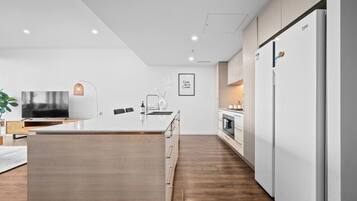 A modern kitchen with a central island, white cabinetry, and a built-in oven.