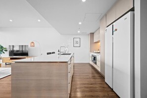 Una cocina moderna con una isla central, armarios blancos y horno empotrado.