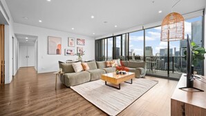 Un salon moderne avec un canapé, une table basse et de grandes fenêtres donnant sur la ville.