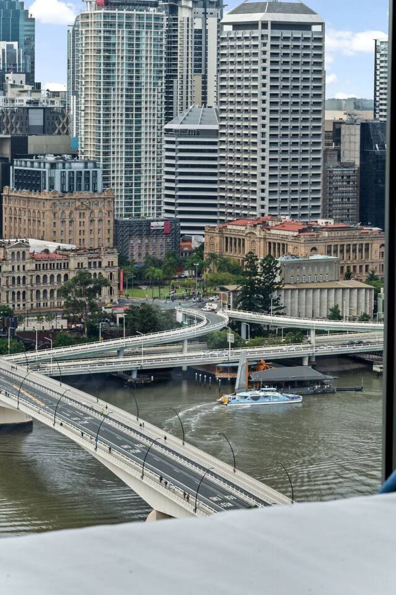 A cityscape with a bridge over water, modern buildings, and a historic building.