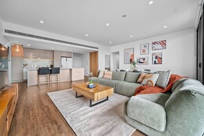 A modern living room with a sectional sofa, a coffee table, and a kitchen in the background.