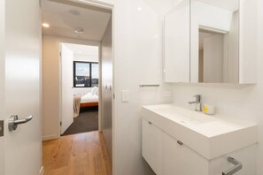 Ein modernes Badezimmer mit Waschbecken, Spiegel und kleinem Fenster.