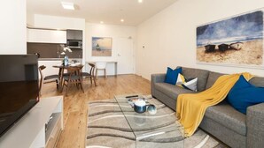 Una sala de estar moderna con un sofá gris, una mesa de centro y un cuadro de una playa.