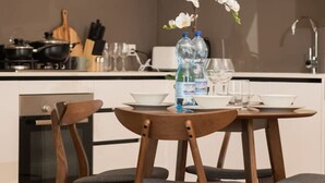 Una cocina moderna con armarios blancos, una mesa de comedor de madera con sillas, y un jarrón con flores blancas.