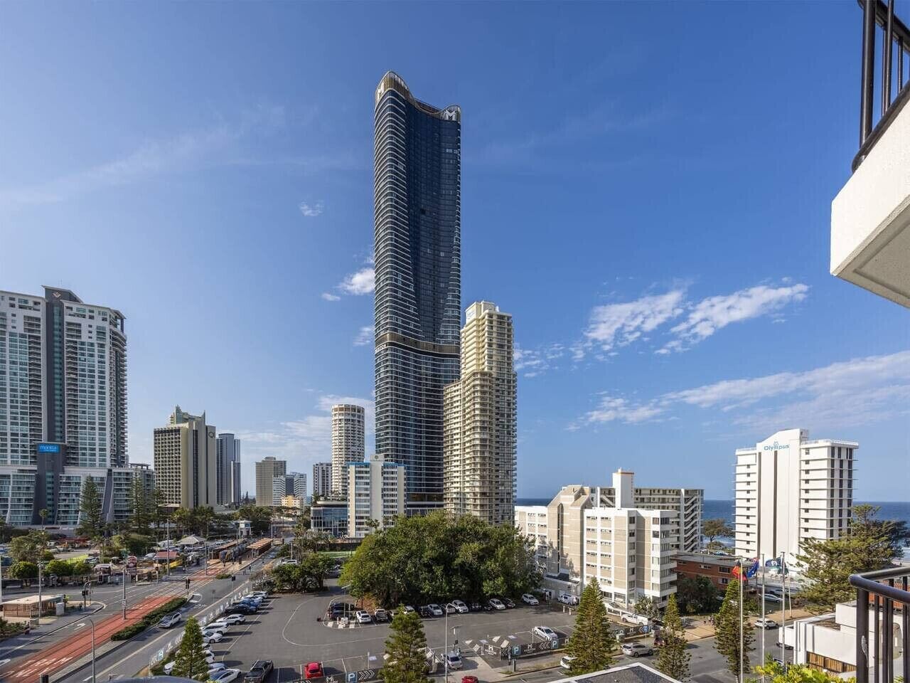 A cityscape with a prominent skyscraper, a parking area, and surrounding buildings.