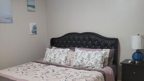A bedroom with a bed, a nightstand, a ceiling fan, and a wall with two pictures. - On The Sand - Oceanfront - Dream Location (Huntington Beach)