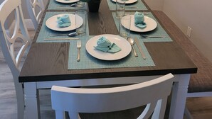 A dining table set with plates, napkins, and a vase of flowers. - On The Sand - Oceanfront - Dream Location (Huntington Beach)