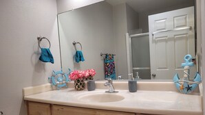 A bathroom with a large mirror, a sink, and wooden cabinets. - On The Sand - Oceanfront - Dream Location (Huntington Beach)