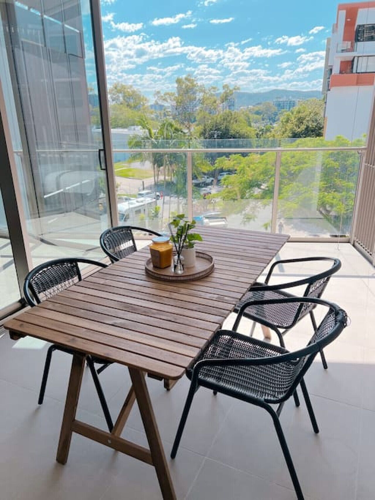 A balcony with a wooden table and chairs, a small plant, and a candle holder.