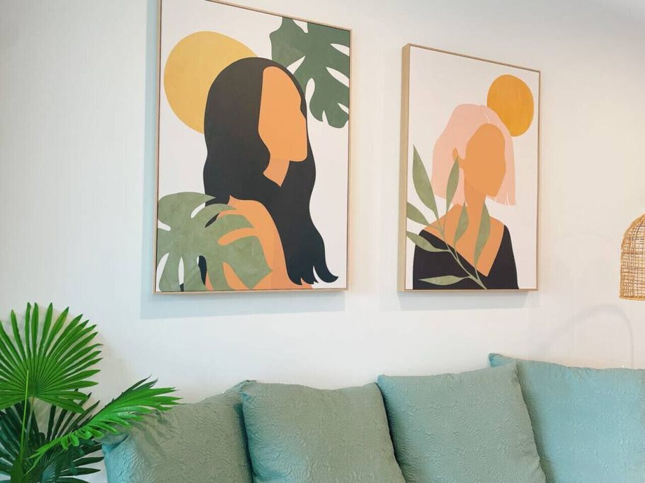 Two framed artworks on a wall above a teal sofa.