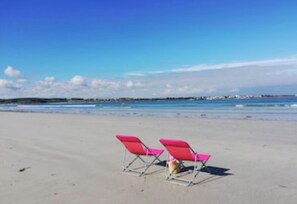 Uma praia com duas cadeiras de praia cor-de-rosa e um céu azul límpido.
