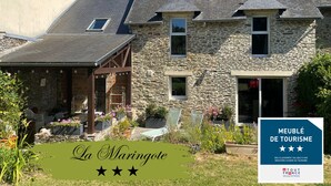 A stone building with a covered patio and outdoor seating area. - La Maringote 3* (Cerisy-la-Forêt)