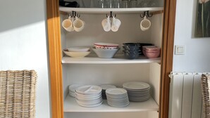 A storage closet with shelves holding plates, bowls, and glassware. - La Maringote 3* (Cerisy-la-Forêt)