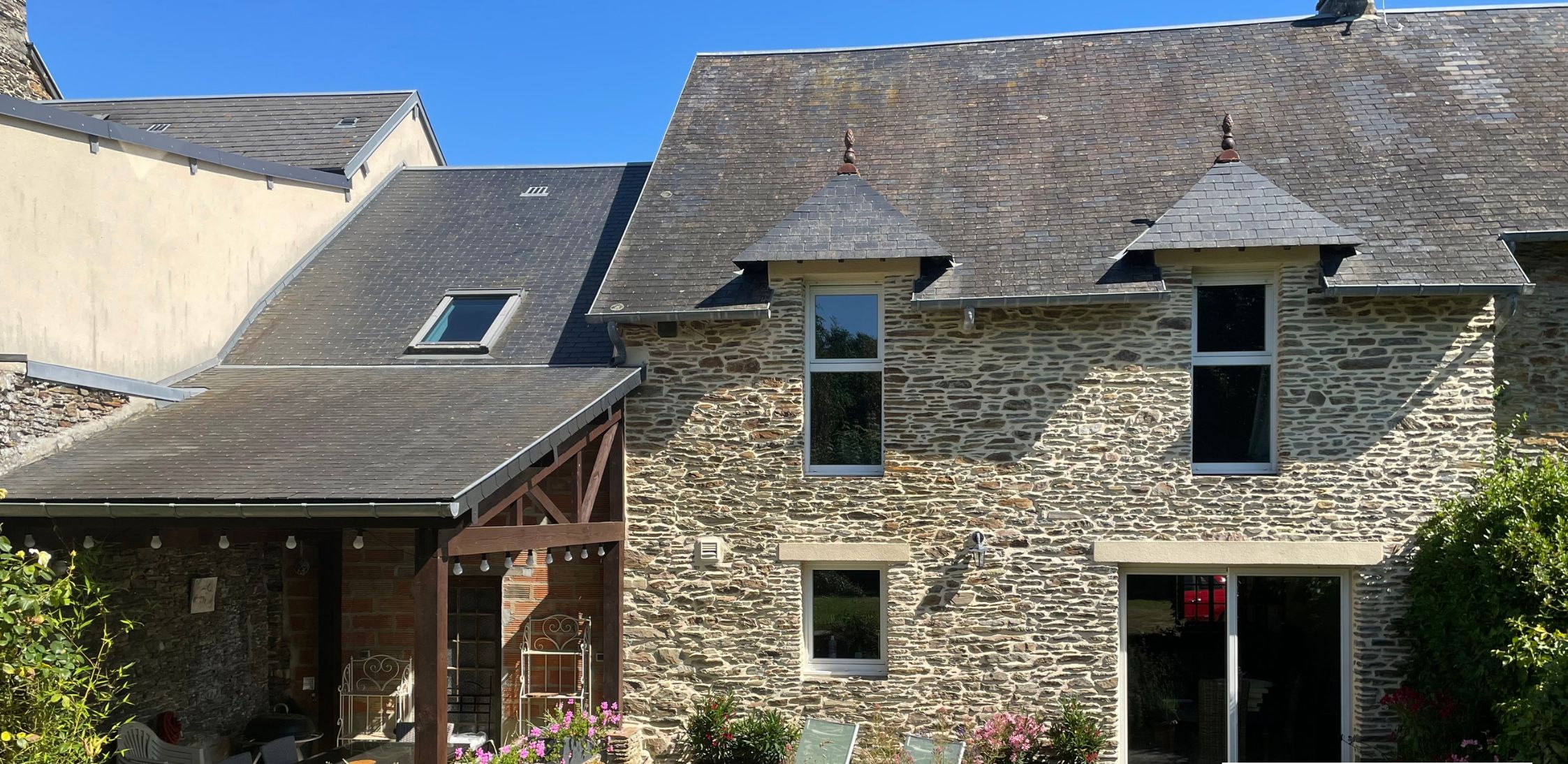 Ein Steinhaus mit überdachter Terrasse und Außenbereich mit Sitzgelegenheiten.