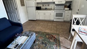 A compact living space with a kitchenette, a sofa, a coffee table, and a dining area. - Cozy cottage by the lake! 18c (Phenix City)