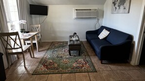 A compact living space with a dining area, a sofa, a coffee table, and a world map on the wall. - Cozy cottage by the lake! 18c (Phenix City)