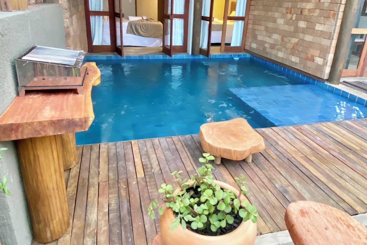 A wooden deck with a pool, a wooden table, and a potted plant.