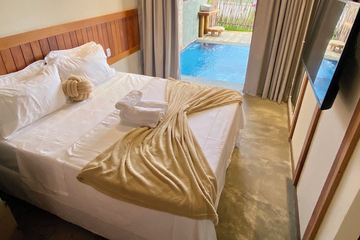 A hotel room with a bed, a TV, and a view of a swimming pool.