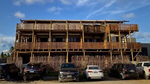 Un immeuble à plusieurs étages, doté d’une façade en bois et de balcons. Plusieurs voitures sont garées devant.
