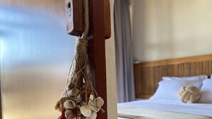 Een hotelkamer met een houten deur, een bed met witte lakens en een decoratieve schelp die aan de deur hangt.