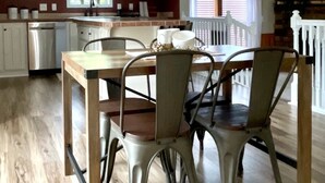 Un comedor con una mesa de madera y sillas de metal, una cocina con armarios blancos y una chimenea de piedra.