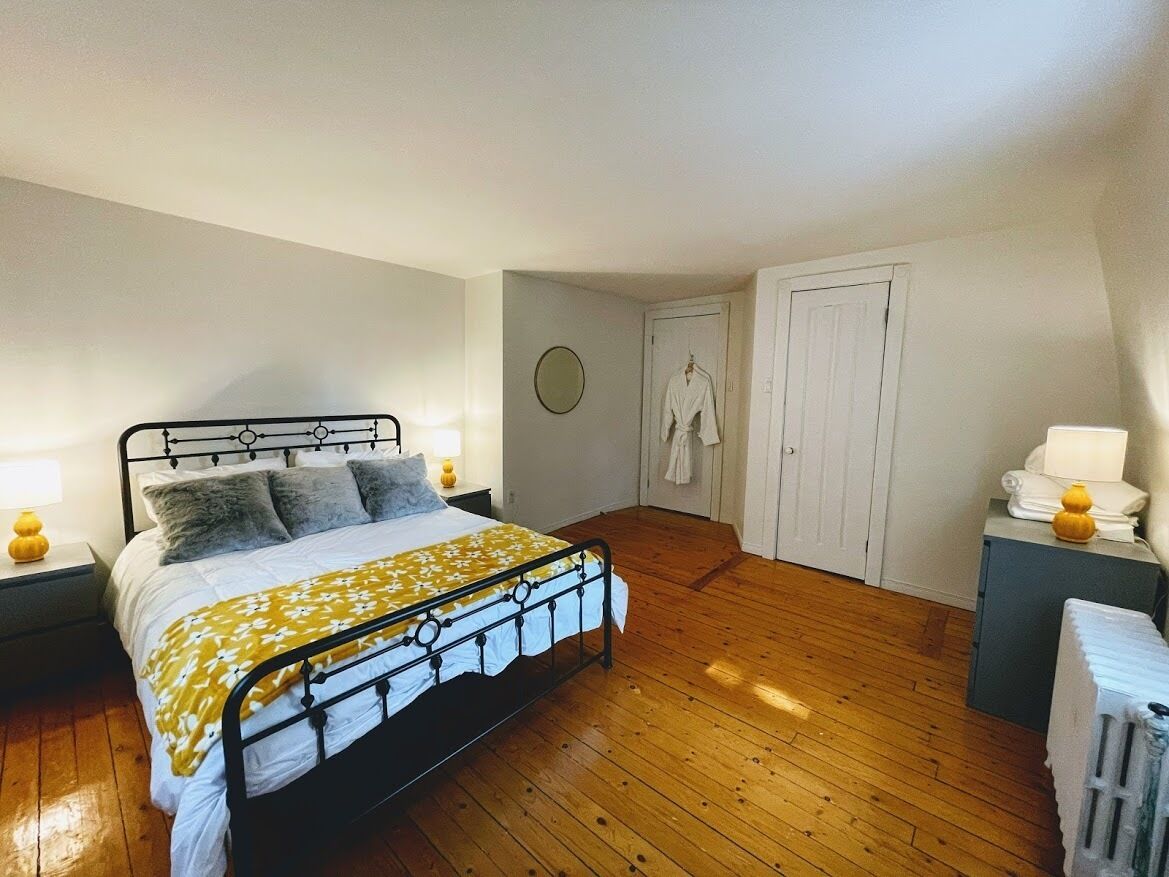 Une chambre à coucher comprenant un lit, des tables de chevet, une armoire et un radiateur.