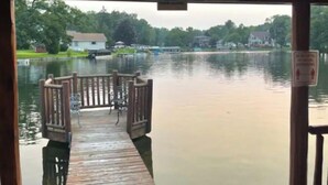 Une jetée en bois s’étendant au-dessus d’un lac paisible, avec des maisons et des arbres visibles au loin.