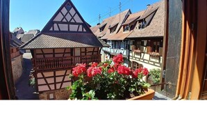 A traditional half-timbered building with a sloped roof and a balcony with potted flowers.