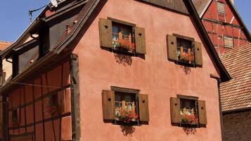 A traditional half-timbered building with stone base, wooden shutters, and flower boxes on the windows.