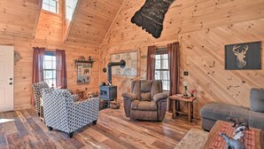Ein gemütliches Blockhaus-Interieur mit Kamin, gemusterten Sofas und einer Bärenstatue.