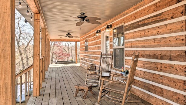 Eine Holzhütte mit Veranda, Schaukelstühlen und Deckenventilator.