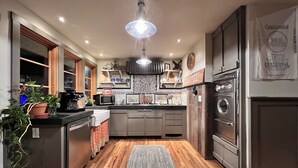 A modern kitchen with wooden flooring, stainless steel appliances, and a central island. - Unique Cottage near Canyon Lands National Park (Monticello)