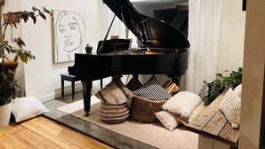 A grand piano in a living room with a modern design, a large window, and a minimalist decor. - Unique Cottage near Canyon Lands National Park (Monticello)