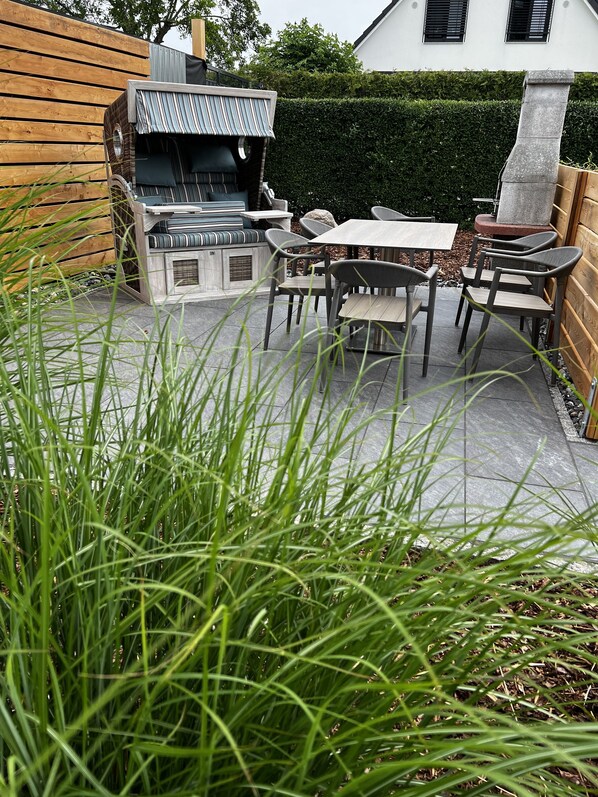 Une terrasse avec un barbecue, une table à manger et des chaises.