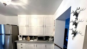 A kitchen with white cabinets, a stainless steel refrigerator, a microwave, and a wooden floor. - Historic Valier Lodge near Lake Francis (Valier)