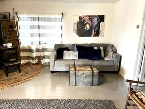 A living room with a grey sofa, a bear painting, a vintage radio, and a rustic coffee table.
