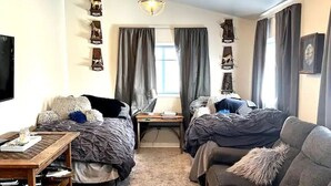A room with two beds, a sofa, a TV, and a table with a lamp. - Historic Valier Lodge near Lake Francis (Valier)