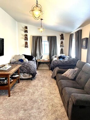 Una habitación con dos camas, un sofá, un televisor y una mesa con lámpara.