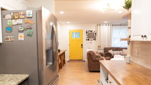 Una cocina moderna con refrigerador, armarios de madera y una puerta amarilla.
