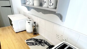 A kitchen with a wooden countertop, a toaster, a coffee maker, and a decorative mat with a crab design. - Cottage set in 2 acres, next to coast path, short walk to beach, pub & cafe! 😎 (Cadgwith)