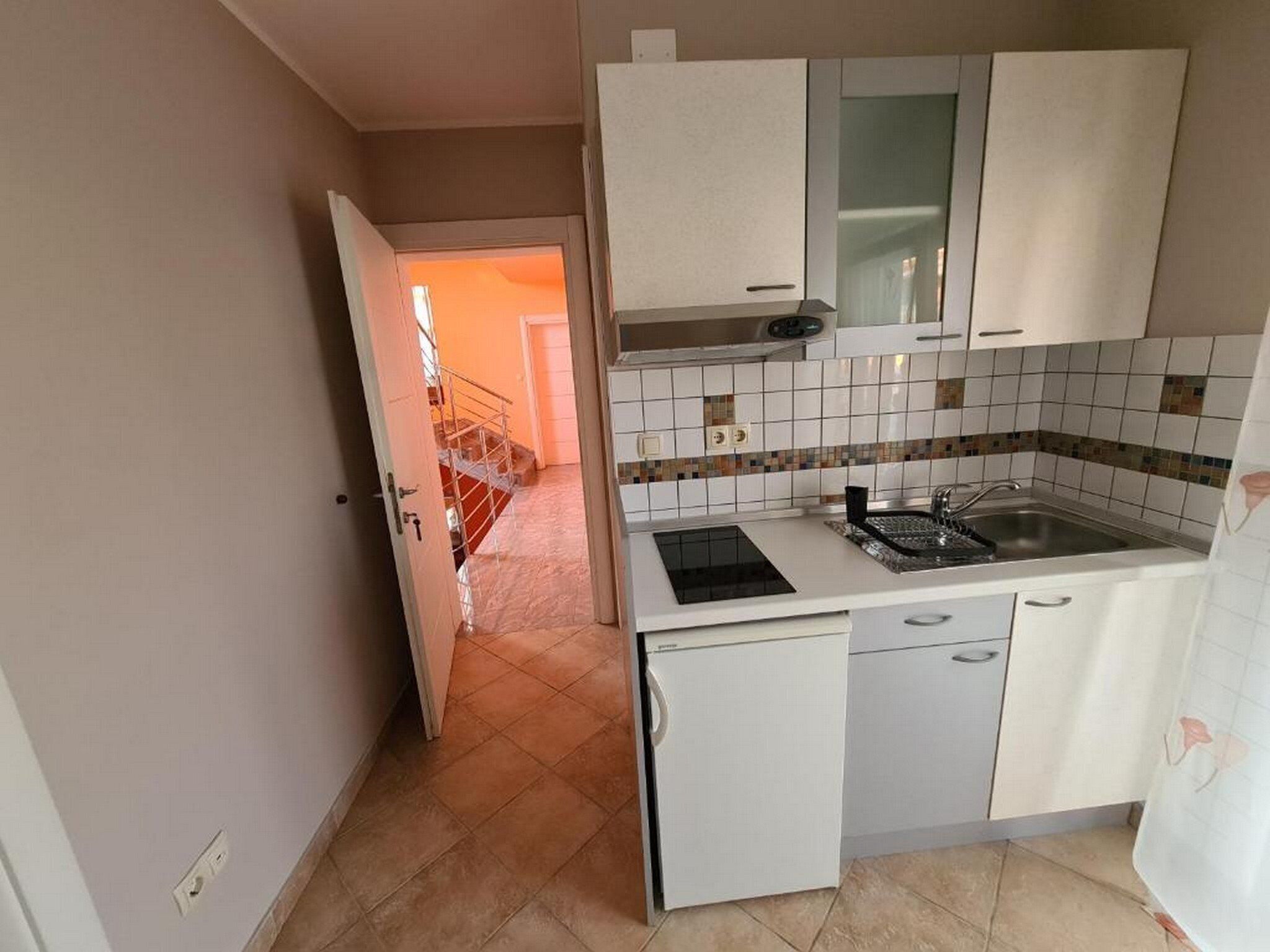 A compact kitchen with white cabinets, a built-in stove, and a sink.
