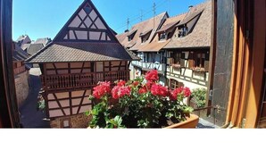 Ein traditionelles Fachwerkhäuschen mit schrägem Dach und einem Balkon mit Blumentöpfen.