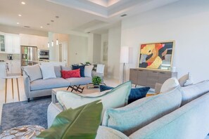 A modern living room with a grey sofa, a coffee table, and a painting on the wall.