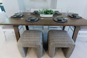 A dining table set with plates, bowls, and glasses, accompanied by a potted plant and a centerpiece.