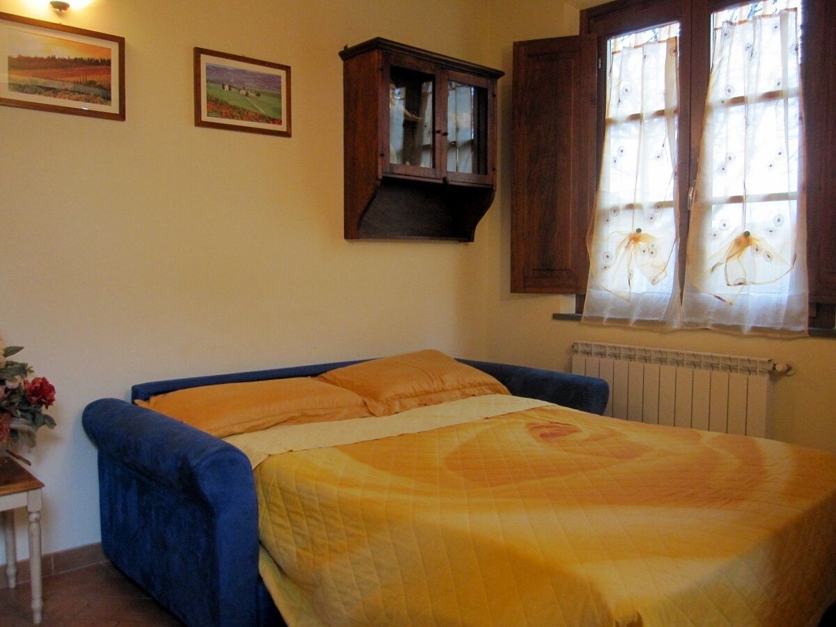 Une chambre à coucher avec un lit, une armoire et une fenêtre avec des rideaux.