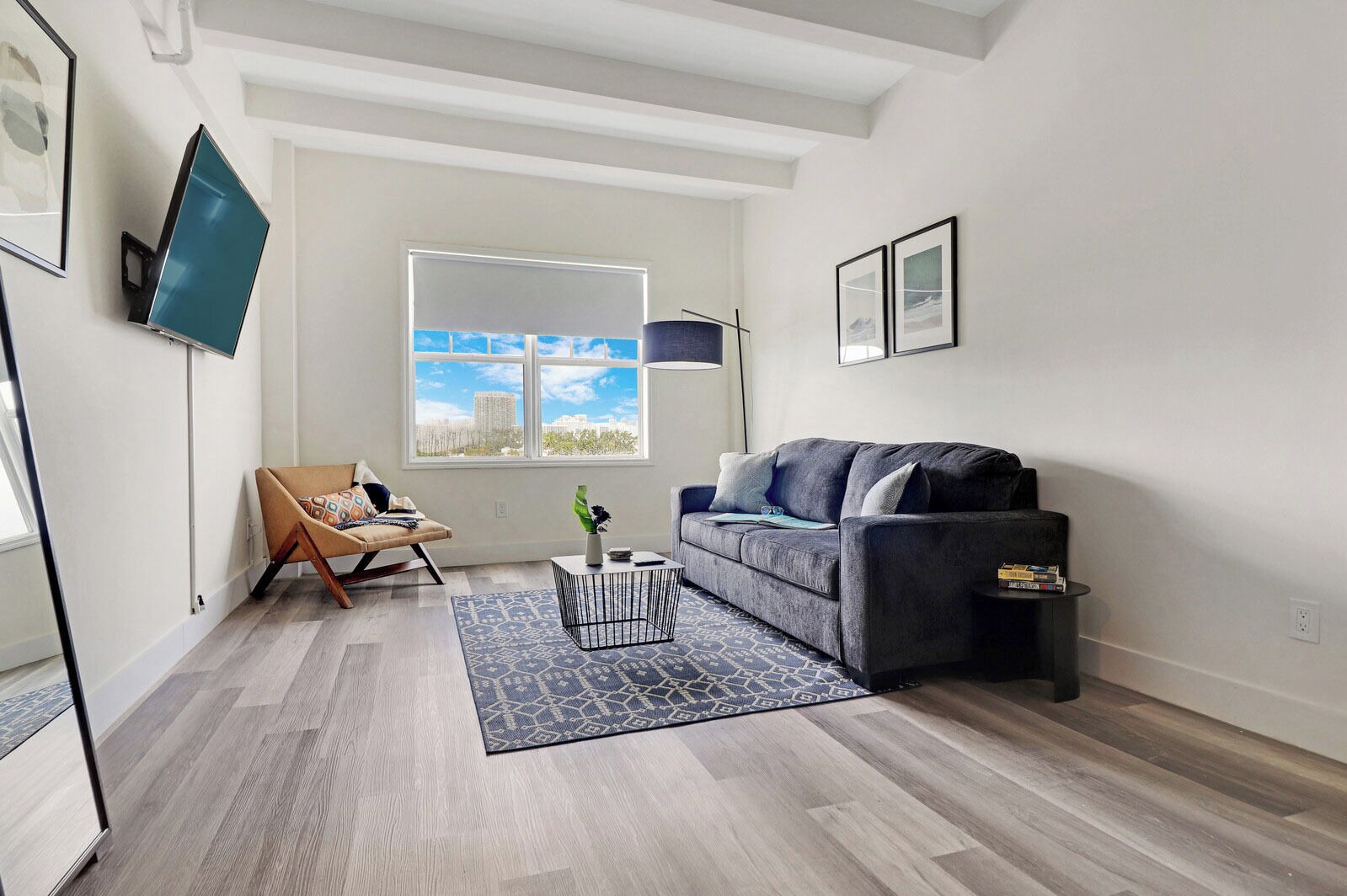 A modern living room with a grey sofa, a patterned rug, a small table, and a chair.