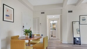 Et moderne spiseområde med et rundt bord, fire sennecgul møbler og en potteplante.