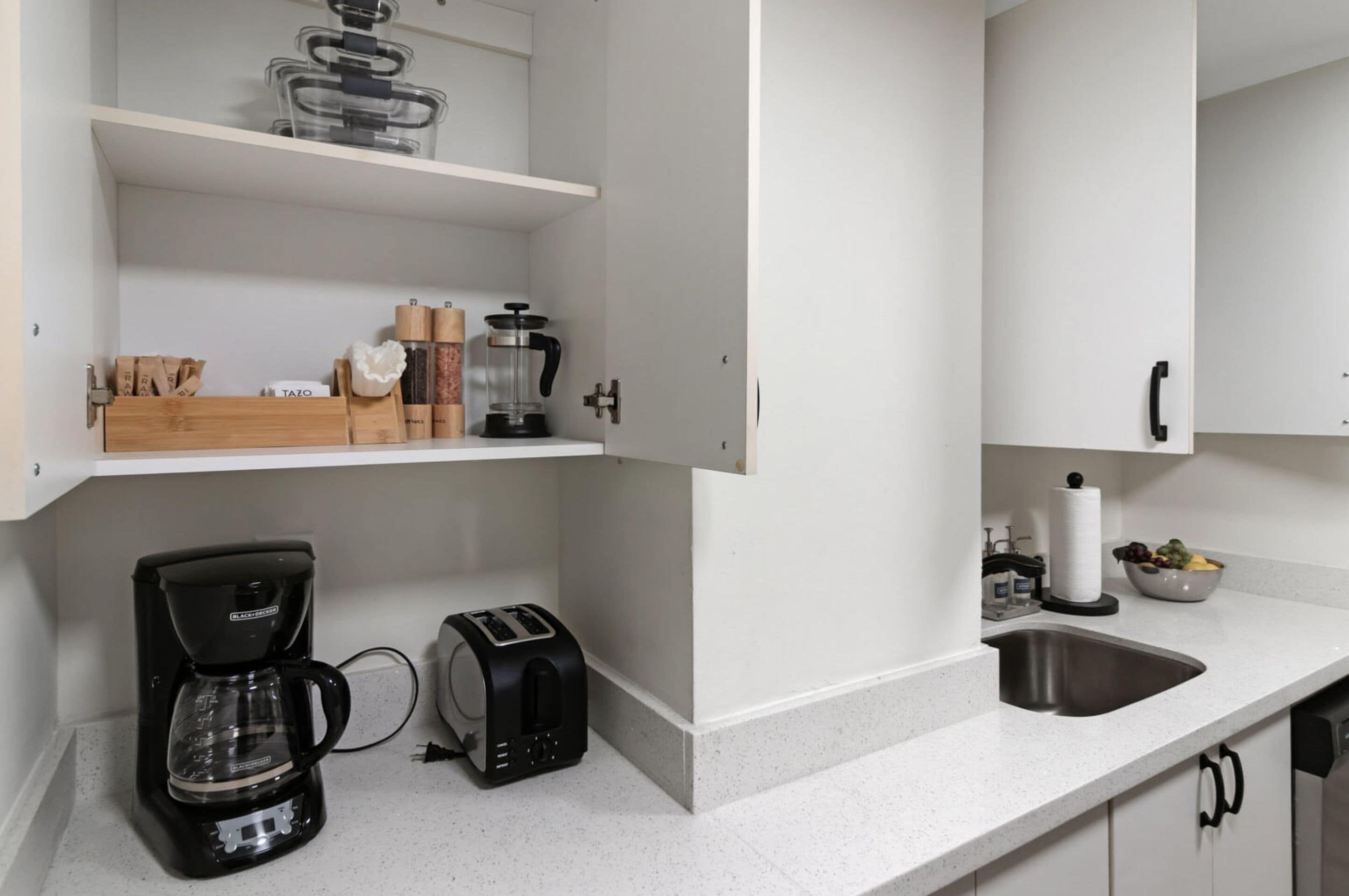 Une cuisine moderne avec des meubles blancs, une machine à café, un grille-pain et un évier.